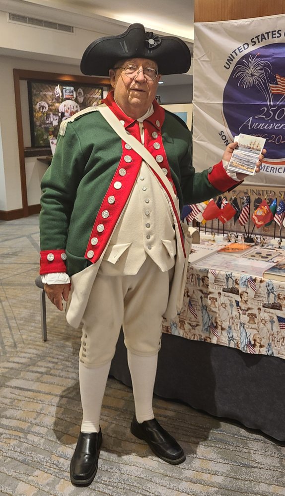 Bill Nay in Revolutionary War Continental Marine uniform promoting the First Amphibious Assault Memorial at 2025 MCL Convention, holding informational materials next to display table